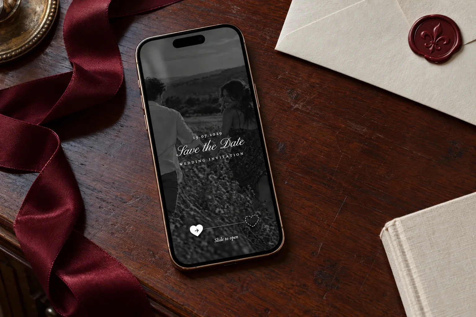 Crimson Vows Save the Date screen on a diagonal phone on a walnut desk beside burgundy ribbon and wax-sealed stationery